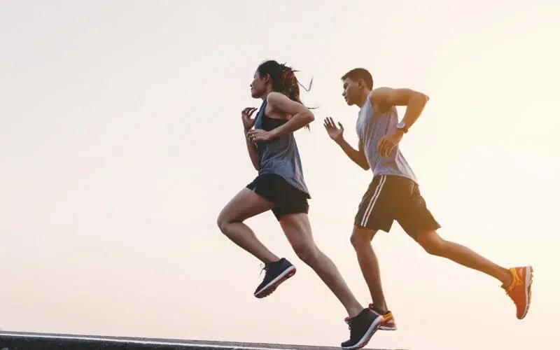 young couple runner running on running road in city park