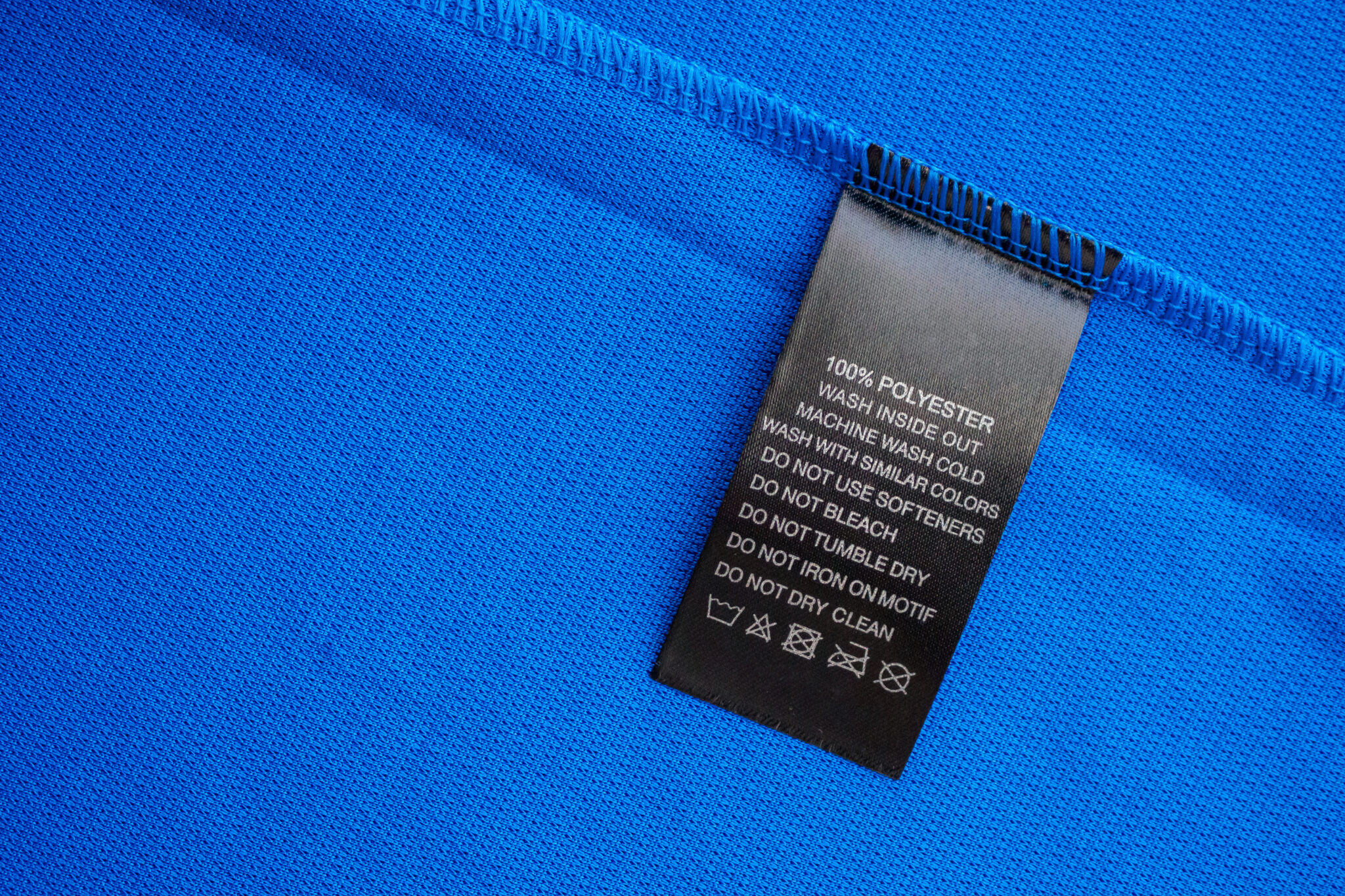 Black laundry care washing instructions clothes label on blue jersey polyester sport shirt