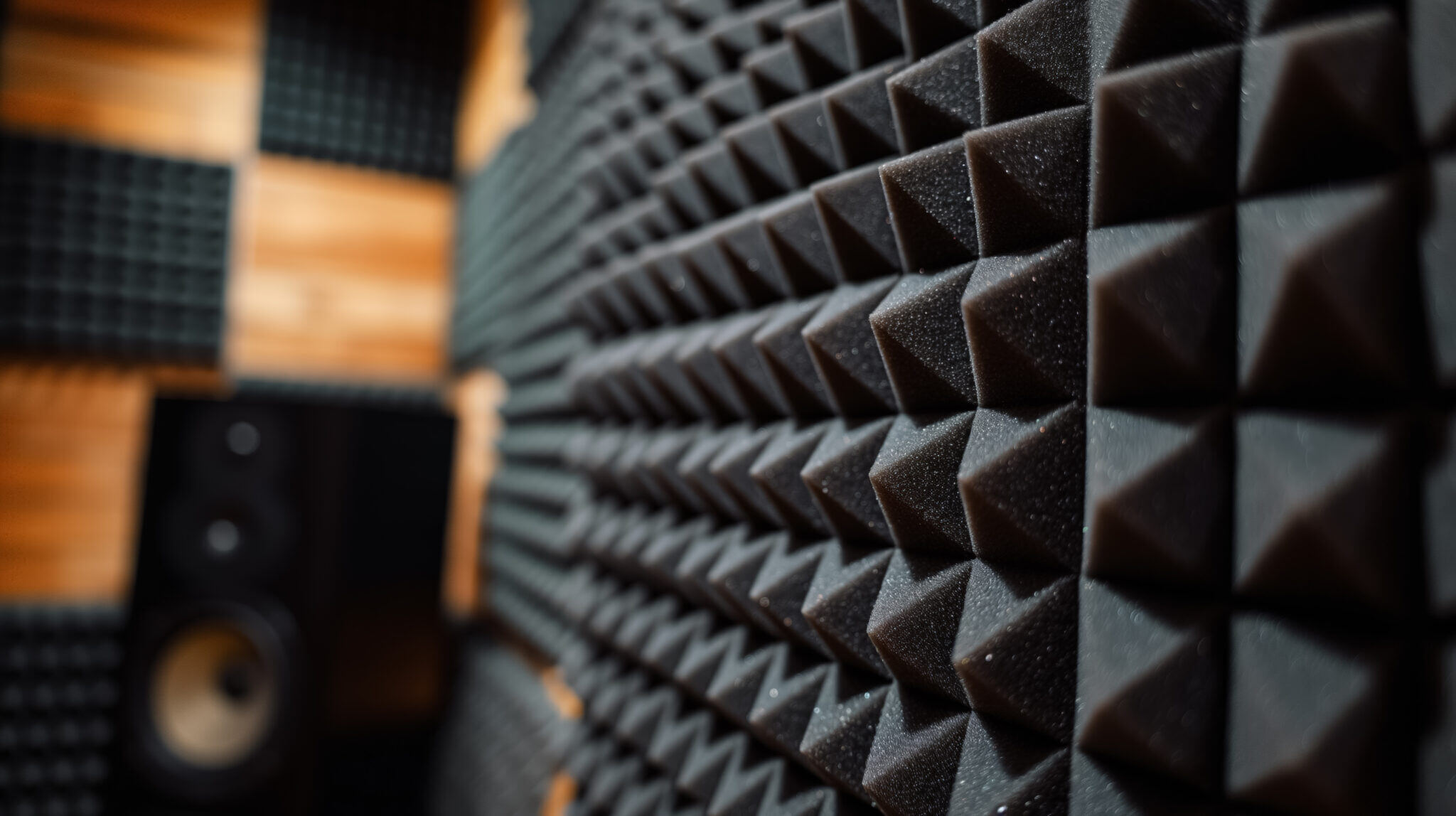 Close-up of a soundproof foam wall, showcasing the geometric patterns of acoustic panels in a recording studio environment.